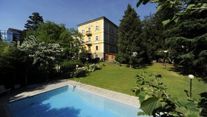 Un hotel con piscina, rodeado de abundante vegetación y árboles.