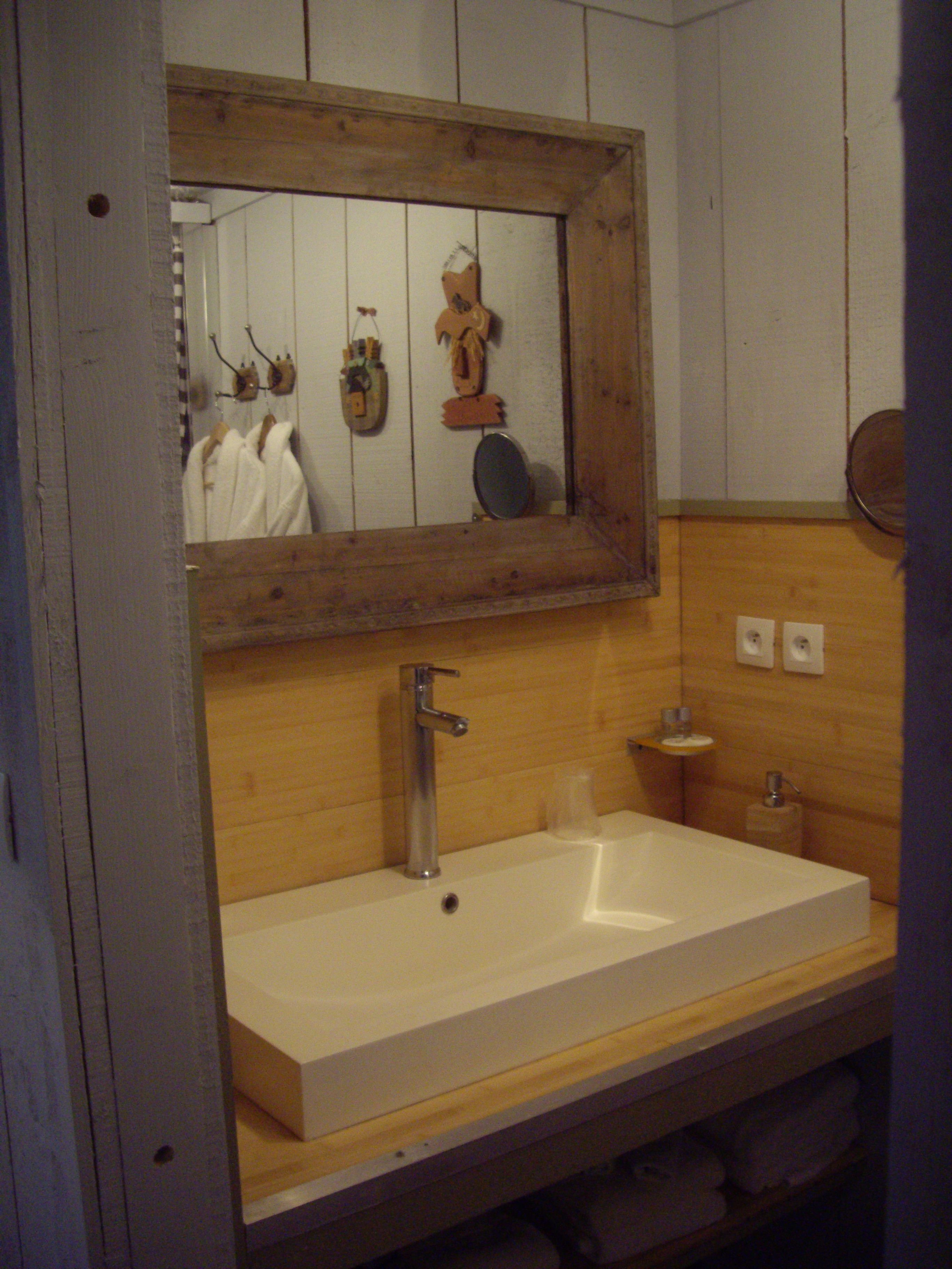 A bathroom with a wooden vanity, a white sink, a mirror, and a towel rack.