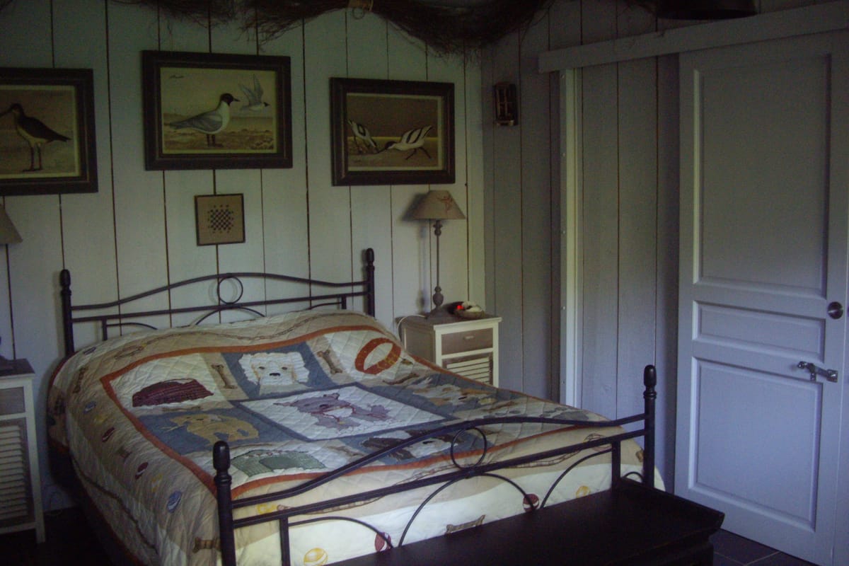 A bedroom with a bed, a nightstand, a lamp, and a door.
