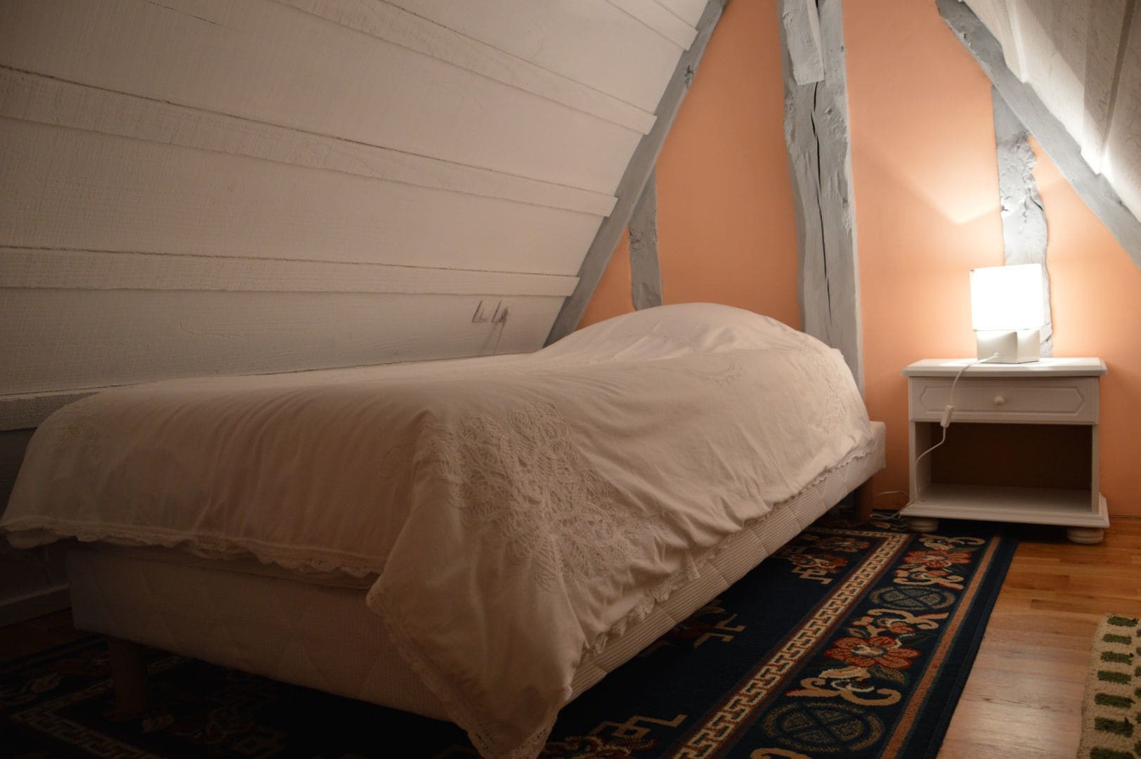A bedroom with a bed, a nightstand, and a lamp.