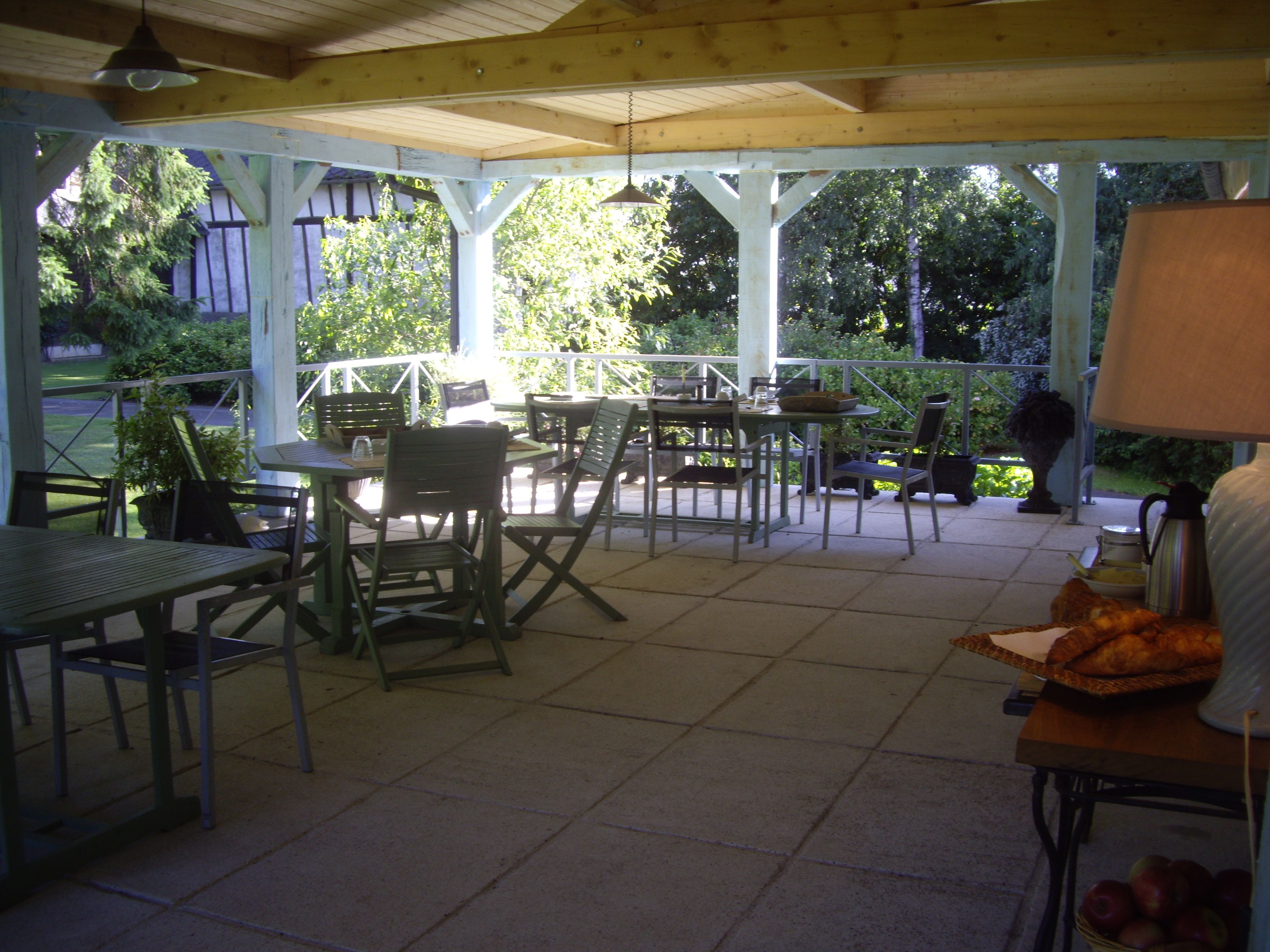An outdoor patio with tables and chairs, surrounded by greenery.