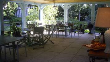An outdoor patio with tables and chairs, surrounded by greenery.