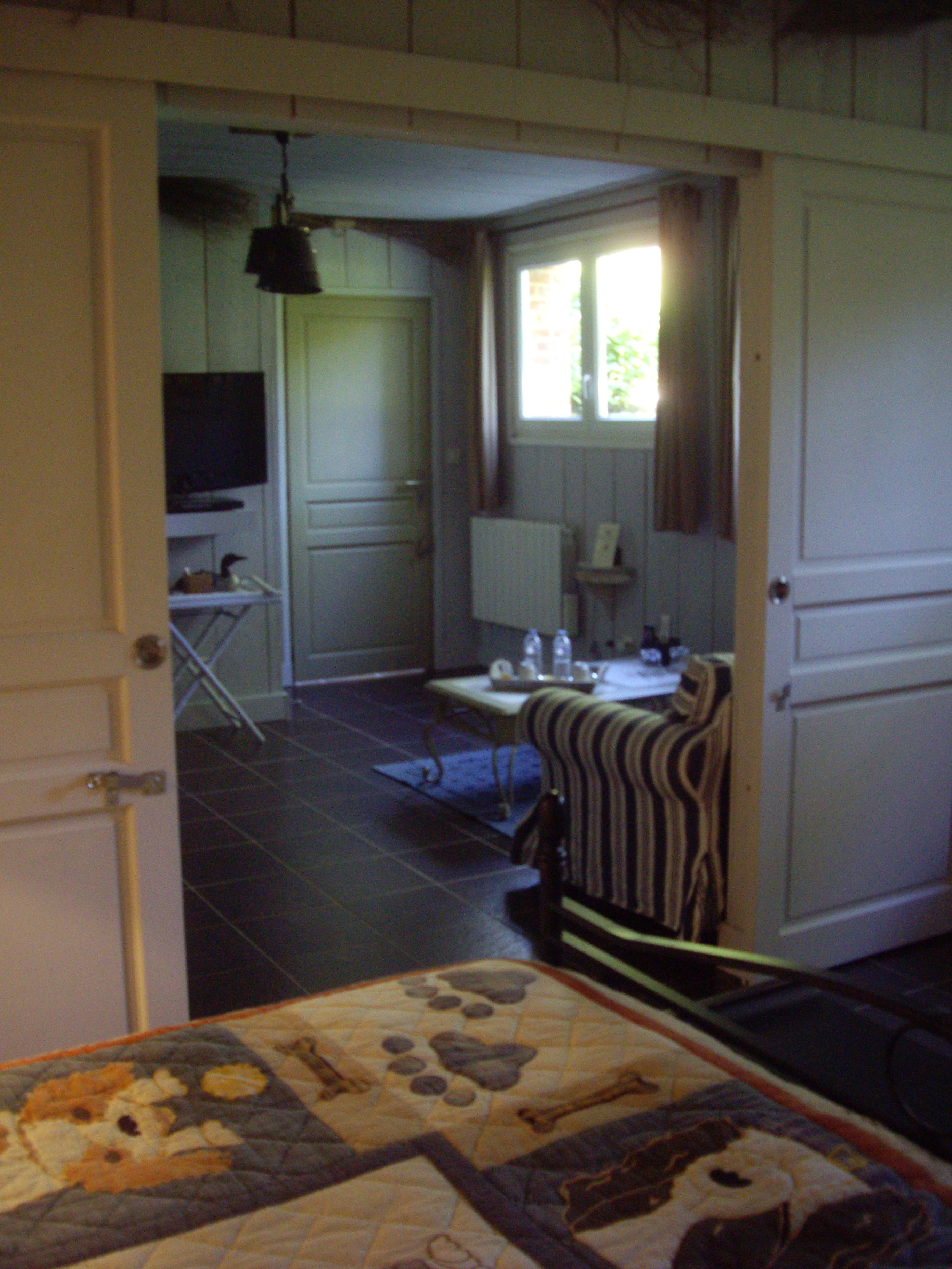 A room with a bed, a chair, a television, a window, and a door.
