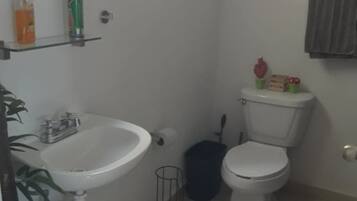 A small bathroom with a sink, toilet, and a window.