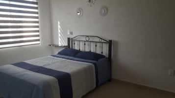 Un dormitorio con cama, ventana con persianas y adornos en la pared.