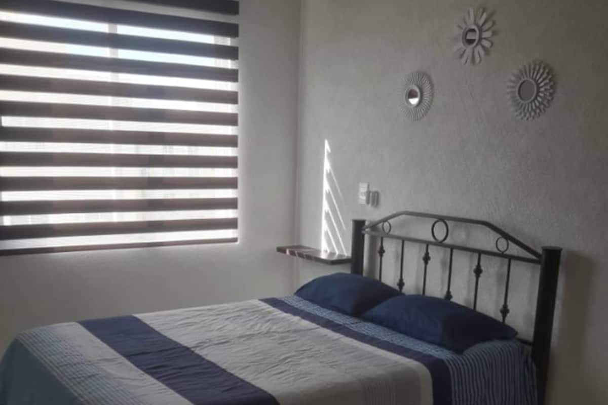 A bedroom with a bed, a window with blinds, and wall decorations.