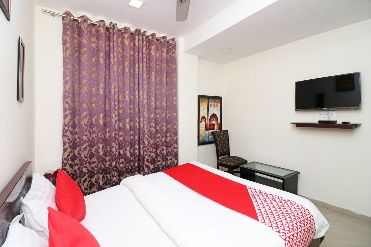 A hotel room with a bed, a TV, a desk, and a chair.