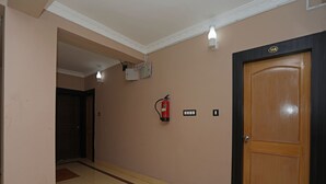 A hallway with a wooden door, a fire extinguisher, and a light fixture. - OYO 11631 Star Inn (Bhubaneshwar)