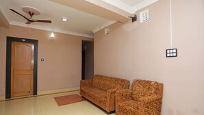A hotel room with a wooden door, a ceiling fan, a patterned sofa, and a tiled floor. - OYO 11631 Star Inn (Bhubaneshwar)