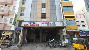 Un edificio con un letrero que indica 'Hotel GMT Centre' y 'Virindhu Veg Restaurant' en la entrada.