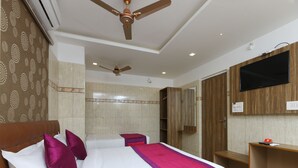 Una habitación de hotel con cama, escritorio, televisor y ventilador de techo.