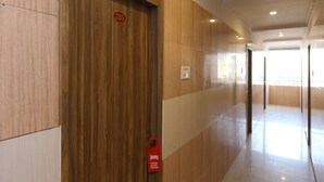 Un pasillo con una puerta de madera numerada 205, un letrero rojo que dice 'No molestar' y un interruptor de luz en la pared.