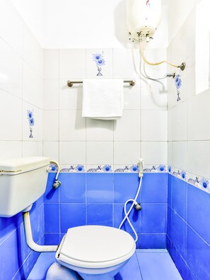 Een badkamer met een wit toilet, blauwe tegels en een witte handdoek aan een stang.