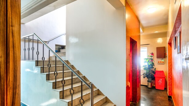 Un interior moderno con una escalera, una pared roja y una planta.