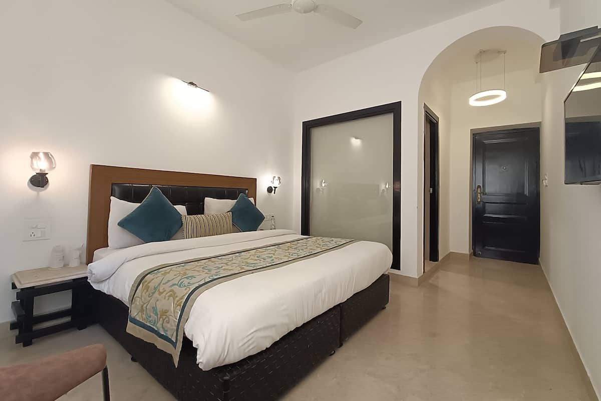 A modern hotel room with a large bed, a ceiling fan, a nightstand, and a wardrobe.