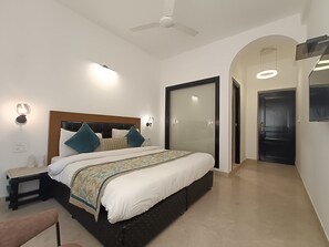 A modern hotel room with a large bed, a ceiling fan, a nightstand, and a wardrobe. - Hotel Green Castle (Heritage Hotel) (New Delhi)