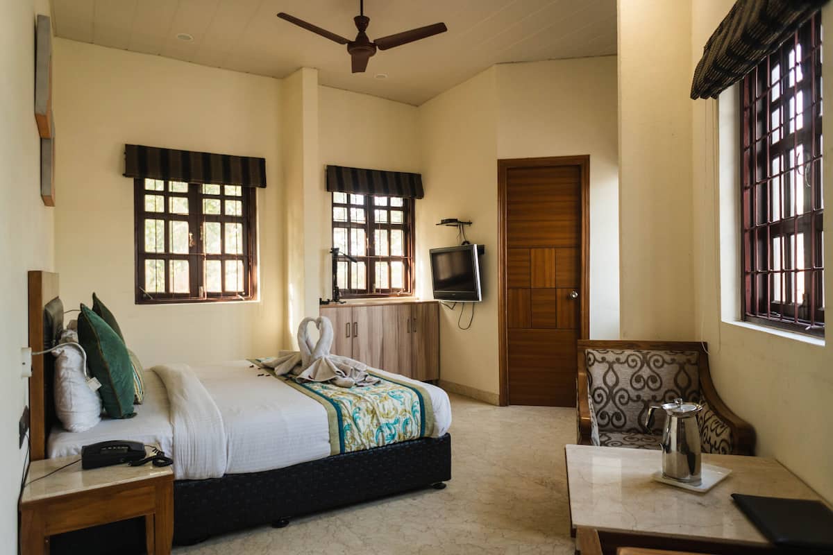 A hotel room with a bed, a television, a coffee table, and a window with bars.