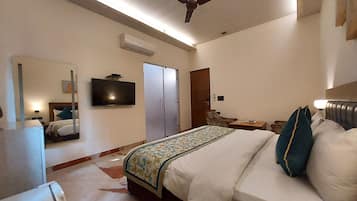 Habitación de hotel con cama, televisor, ventilador de techo, armario y escritorio con silla.