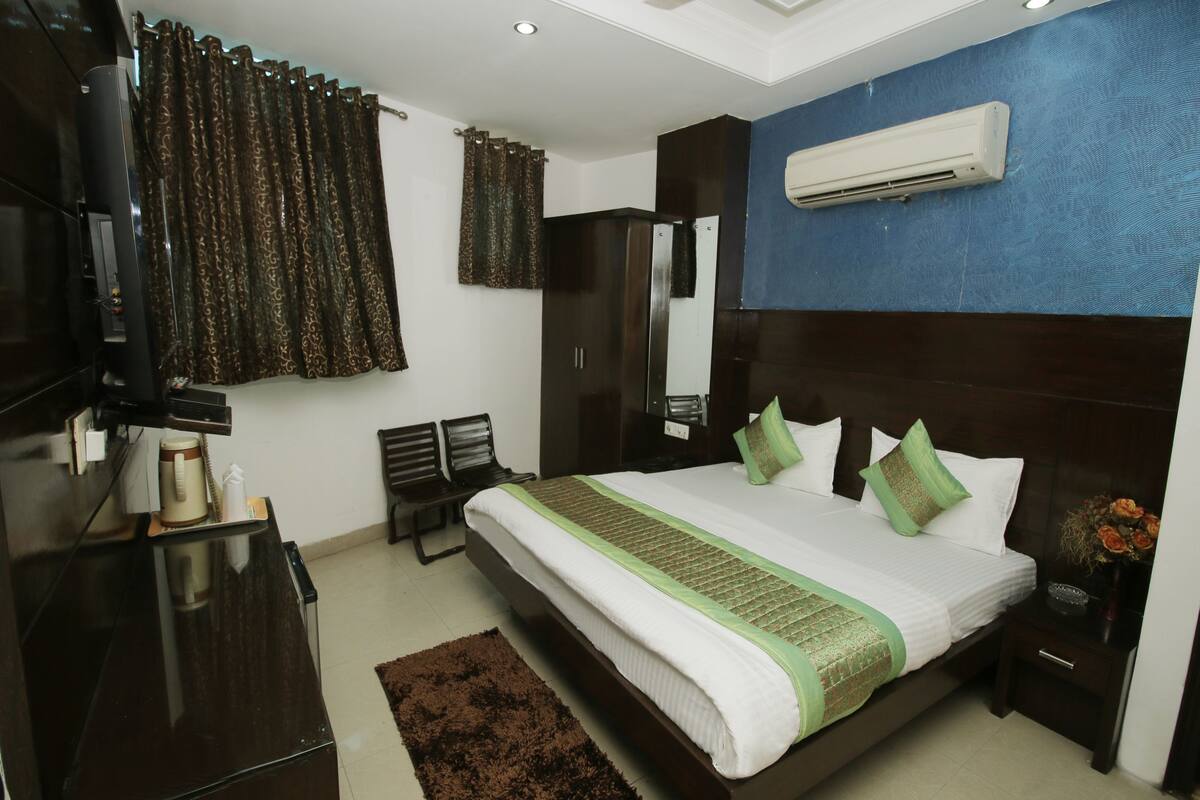 Een slaapkamer met een groot bed, een televisie, een kledingkast en een airconditioning.