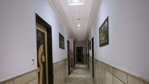 Un pasillo con suelo de mármol, puertas y cuadros en las paredes.