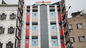 Un hotel de varios pisos con una banda vertical central de ventanas y un cartel que indica que es el "Hotel Delhi Heart Delhi Ka Tadka".