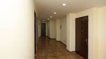 A hallway with wooden flooring, cream-colored walls, and a door at the end.