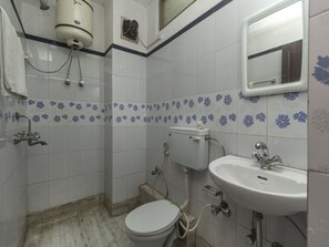 Un baño pequeño y sencillo con inodoro, lavamanos y ducha.