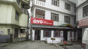 Hotel OYO Hotel White Mountain con un letrero, una entrada con portón y una camioneta estacionada afuera.