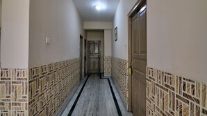 Un pasillo con paredes estampadas, una puerta de madera y un accesorio de iluminación en el techo.