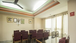 Un salón de conferencias con una mesa de vidrio, sillas de madera y un ventilador de techo.