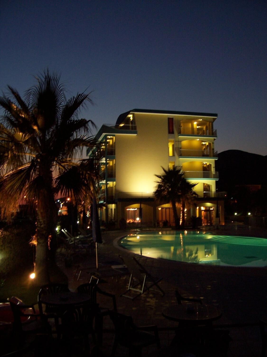 A multi-story hotel with a pool area, palm trees, and outdoor seating.