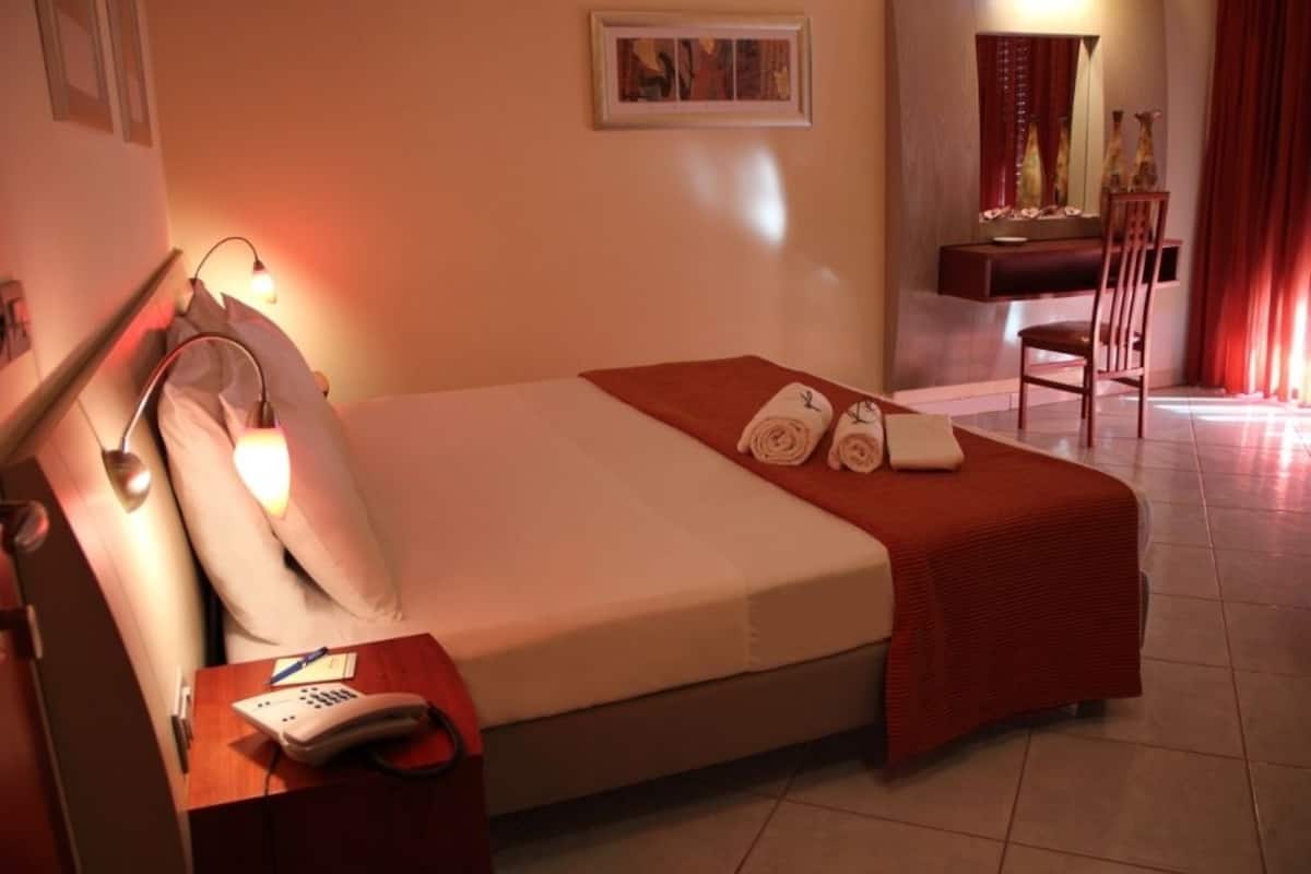Une chambre d’hôtel comprenant un lit, une table de chevet avec un téléphone, une chaise et un bureau avec un miroir.