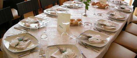 A dining table set for a formal meal with multiple place settings, glasses, and a menu stand.