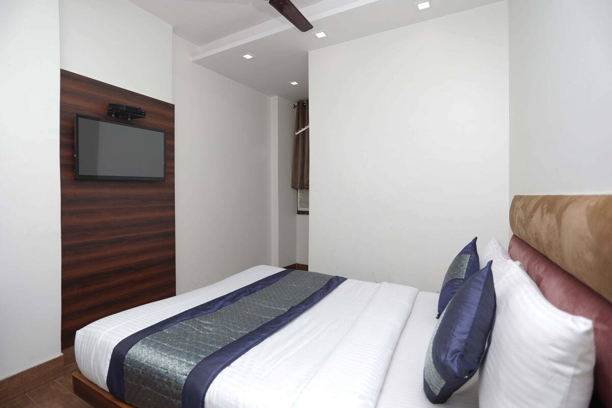 Een moderne hotelkamer met een groot bed, een wandtelevisie en een houten hoofdeinde.