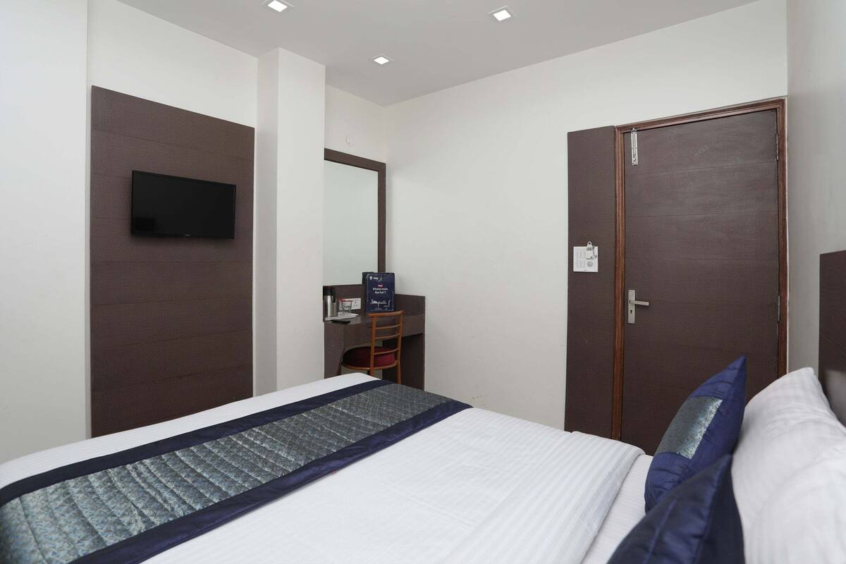 Een hotelkamer met een bed, een bureau, een stoel, een televisie en een kledingkast.