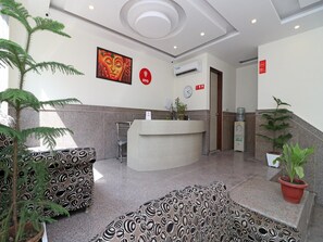 A reception area with a modern design, including a reception desk, a clock, and a Buddha painting on the wall. - OYO 12754 Hotel The Best (New Delhi)