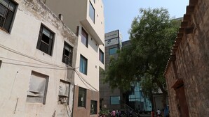 Una calle estrecha flanqueada por edificios, entre ellos un inmueble moderno con un anuncio de Asia Shipping.