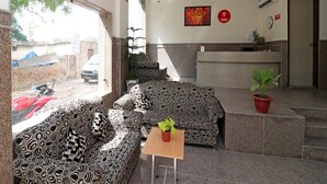 Vestíbulo de hotel con sofás estampados, una mesa de recepción y una planta en maceta.