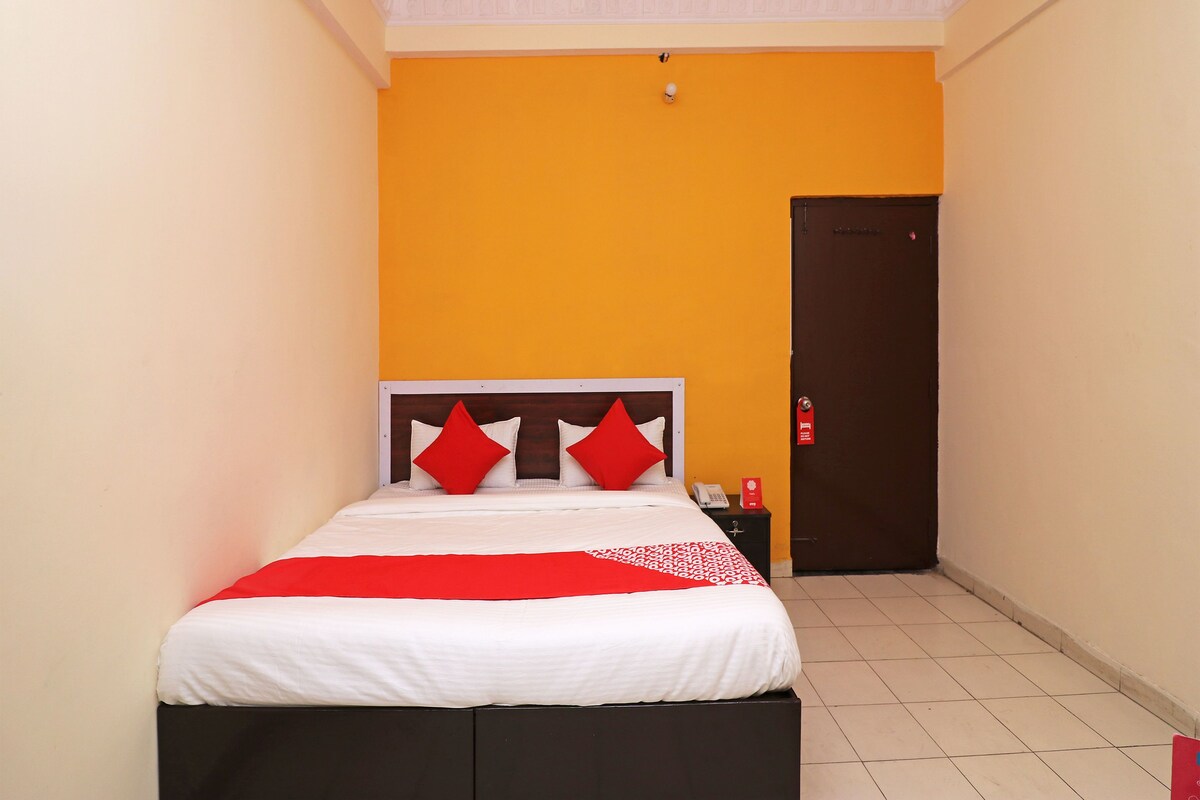 A hotel room with a bed, a nightstand, and a door.
