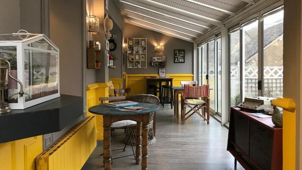 A cozy interior with a dining area, a kitchen counter, and a large window offering a view of the outside. - A La Lettre Thé (Valencisse)