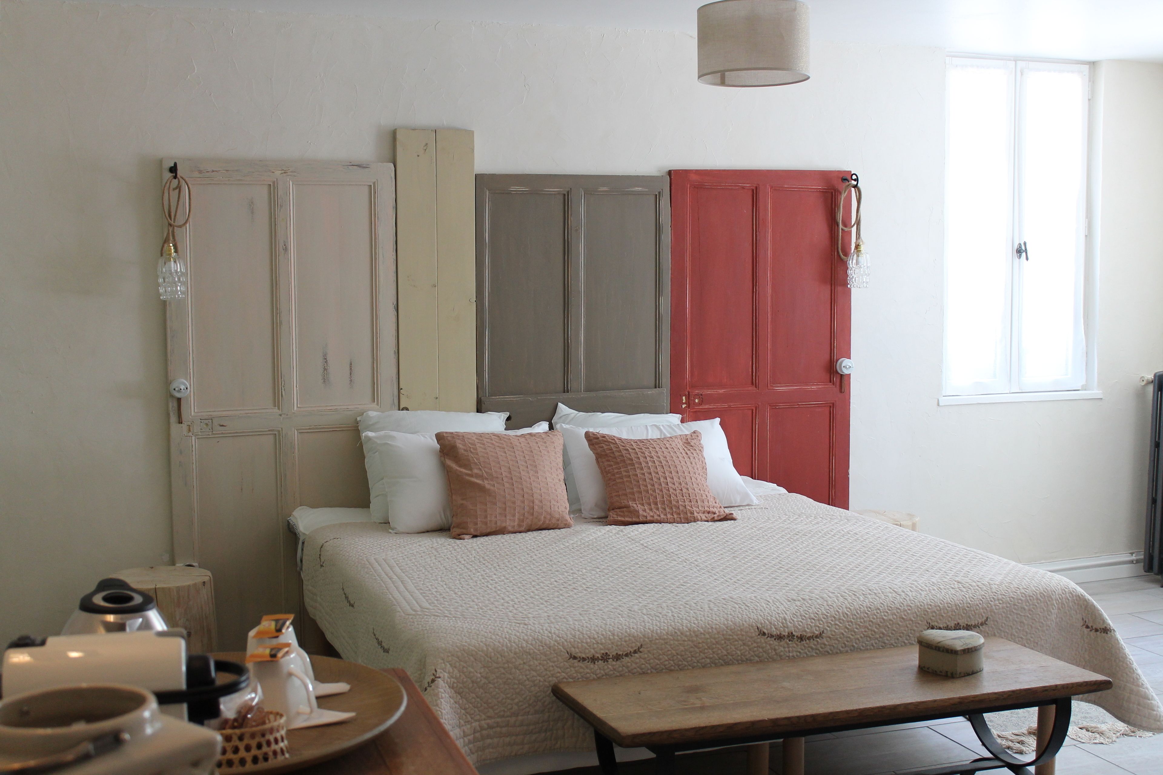 Un dormitorio con cama, mesita de noche y ventana.