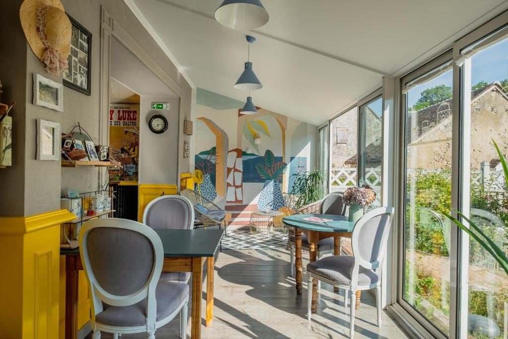 A dining area with a table and chairs, a mural on the wall, and a view through large windows.