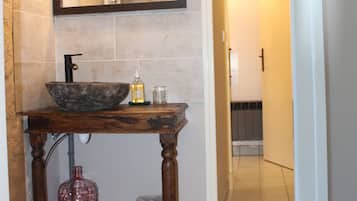 A bathroom with a wooden vanity, a large mirror, and a sink.