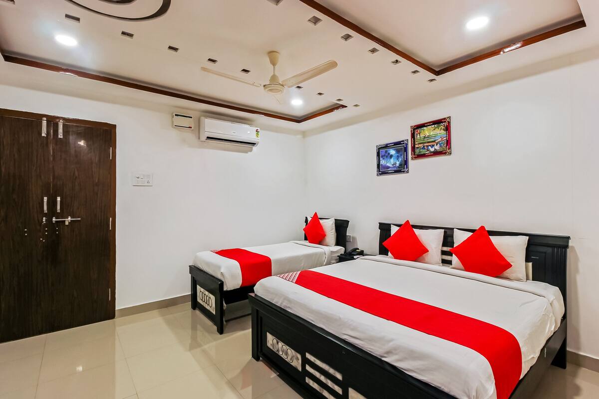 A hotel room with two beds, a ceiling fan, an air conditioning unit, and a door.