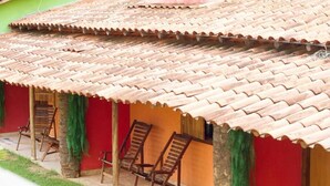 Un edificio con techo de tejas y paredes rojas, que presenta sillas de madera y una puerta pequeña.