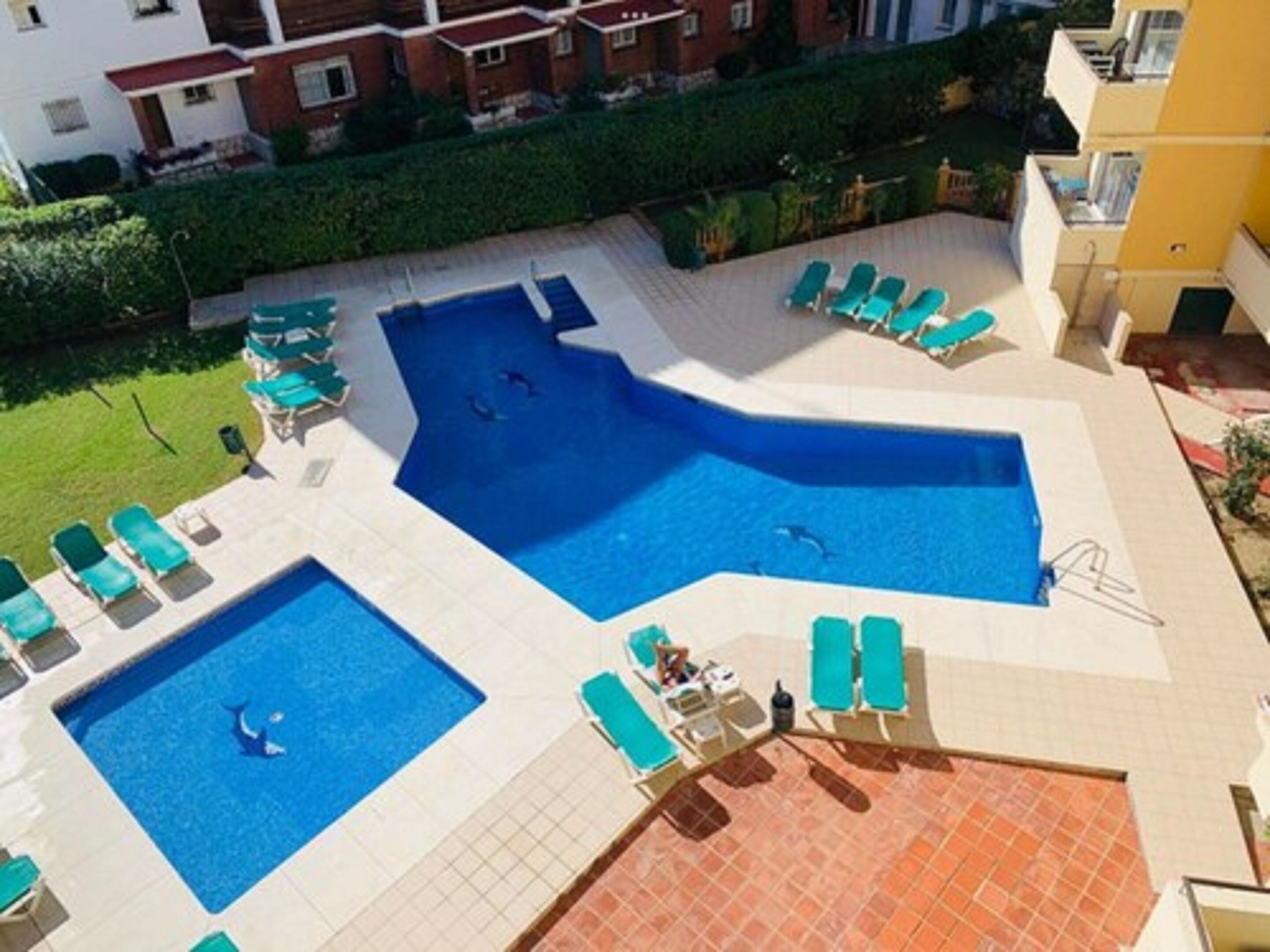 A rooftop swimming pool with multiple sections and lounge chairs.