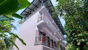 Un immeuble à plusieurs étages doté de balcons, entouré d’une végétation luxuriante.