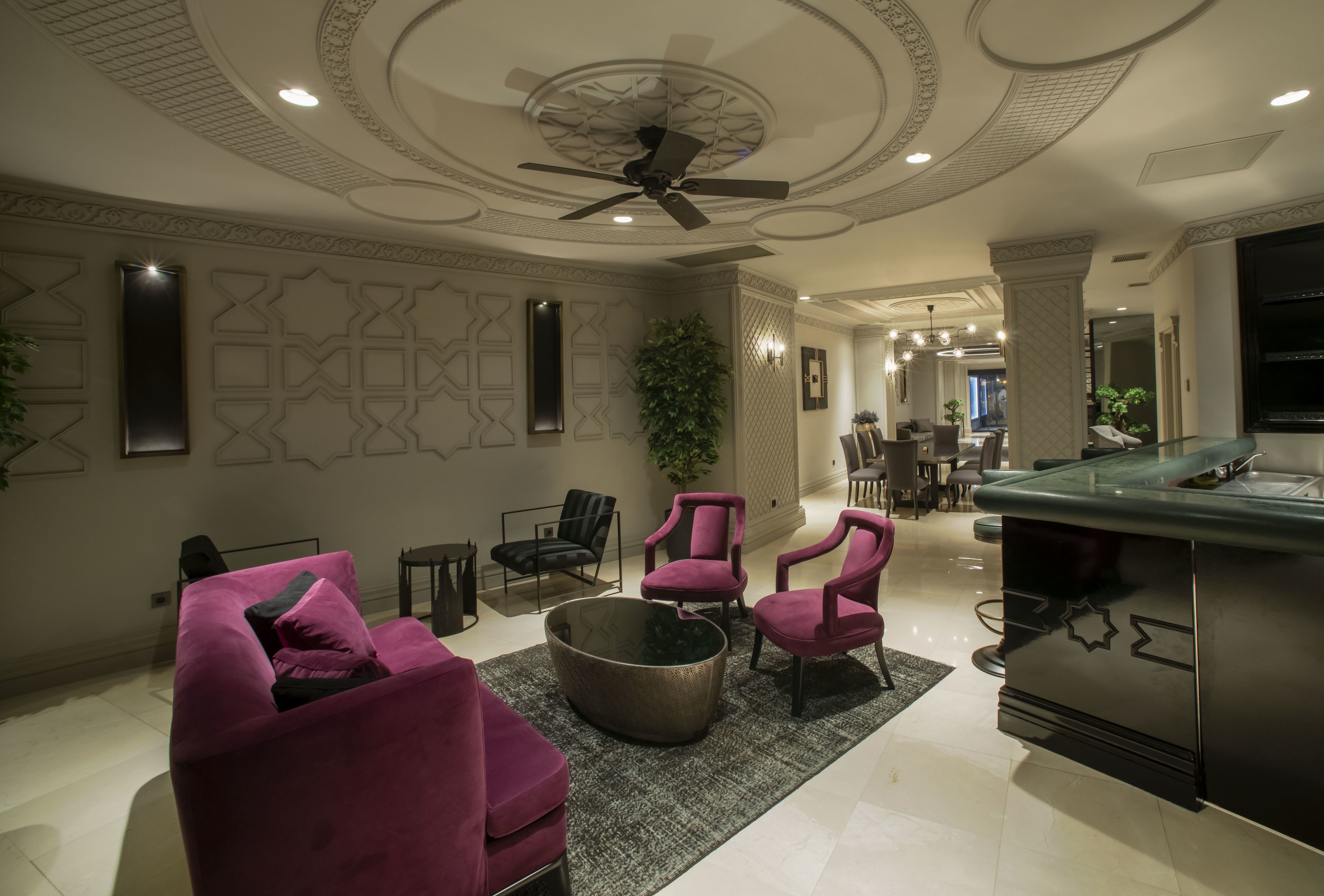 A modern living room with a ceiling fan, a bar area, and a dining space.