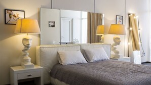 A neatly arranged hotel room with a large bed, two bedside tables with lamps, a mirror, and a door. - Bono Beach Hotel (Odesa)