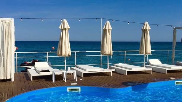 A poolside area with lounge chairs and umbrellas, overlooking the sea. - Bono Beach Hotel (Odesa)